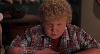 Movie still from “Bad Santa” (2003), directed by Terry Zwigoff – A boy with blonde curly hair sitting at a table; Close Up shot, High angle