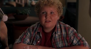 Movie still from “Bad Santa” (2003), directed by Terry Zwigoff – A young boy sitting at a table with a glass; Close Up shot, High angle