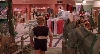 Movie still from “Bad Santa” (2003), directed by Terry Zwigoff – A young boy is looking at clothes on display in a store; Wide shot, Over the shoulder angle