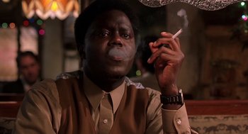 Movie still from “Bad Santa” (2003), directed by Terry Zwigoff – A man smoking a cigarette while sitting at a table; Close Up shot, Low angle