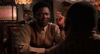 Movie still from “Bad Santa” (2003), directed by Terry Zwigoff – A man sitting at a table with a cigarette in his mouth; Close Up shot, Over the shoulder angle