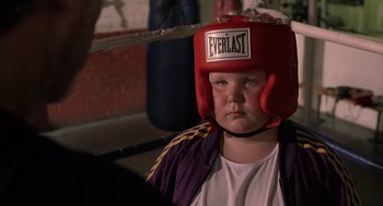 Movie still from “Bad Santa” (2003), directed by Terry Zwigoff – A young boy wearing a red boxing helmet; Close Up shot, Over the shoulder angle