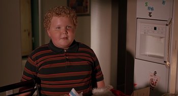 Movie still from “Bad Santa” (2003), directed by Terry Zwigoff – A boy with curly blonde hair wearing a black and red striped shirt; Close Up shot, High angle