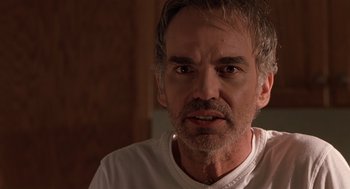 Movie still from “Bad Santa” (2003), directed by Terry Zwigoff – A person wearing a white t - shirt; Close Up shot, Over the shoulder angle