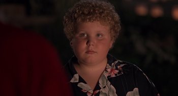 Movie still from “Bad Santa” (2003), directed by Terry Zwigoff – A boy with curly blonde hair wearing a hawaiian shirt; Close Up shot, High angle