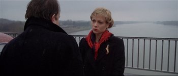 Movie still from “Bad Timing: A Sensual Obsession” (1980), directed by Nicolas Roeg – A woman wearing a red scarf standing next to a man; Close Up shot, Over the shoulder angle