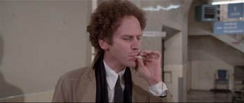 Movie still from “Bad Timing: A Sensual Obsession” (1980), directed by Nicolas Roeg – A man with curly hair is smoking a cigarette; Medium shot, Low angle
