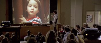Movie still from “Bad Timing: A Sensual Obsession” (1980), directed by Nicolas Roeg – A man standing in front of a projector screen; Wide shot, High angle