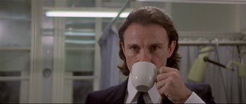 Movie still from “Bad Timing: A Sensual Obsession” (1980), directed by Nicolas Roeg – A man in a suit and tie drinking a cup of coffee; Close Up shot, Low angle
