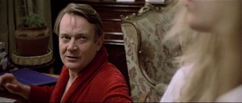 Movie still from “Bad Timing: A Sensual Obsession” (1980), directed by Nicolas Roeg – A man in a red robe sitting in front of a chair; Close Up shot, Over the shoulder angle