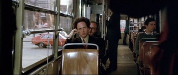 Movie still from “Bad Timing: A Sensual Obsession” (1980), directed by Nicolas Roeg – A man in a suit and tie sitting on a bus; Medium shot, Over the shoulder angle