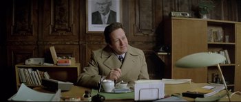 Movie still from “Bad Timing: A Sensual Obsession” (1980), directed by Nicolas Roeg – A man sitting at a table with a cup of coffee; Medium shot, Over the shoulder angle