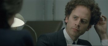 Movie still from “Bad Timing: A Sensual Obsession” (1980), directed by Nicolas Roeg – A person wearing a suit holding a cup; Close Up shot, Over the shoulder angle