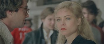 Movie still from “Bad Timing: A Sensual Obsession” (1980), directed by Nicolas Roeg – A woman with blonde hair and red lipstick looking at the camera; Close Up shot, Over the shoulder angle