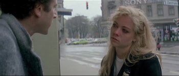 Movie still from “Bad Timing: A Sensual Obsession” (1980), directed by Nicolas Roeg – A woman standing next to a traffic light on a street; Close Up shot, Over the shoulder angle