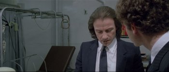 Movie still from “Bad Timing: A Sensual Obsession” (1980), directed by Nicolas Roeg – A man in a suit sitting in front of a chair; Close Up shot, Over the shoulder angle