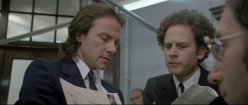 Movie still from “Bad Timing: A Sensual Obsession” (1980), directed by Nicolas Roeg – Two men in business suits are looking at a newspaper; Close Up shot, Low angle