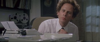 Movie still from “Bad Timing: A Sensual Obsession” (1980), directed by Nicolas Roeg – A man sitting at a desk in front of plates; Close Up shot, Low angle