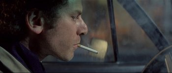 Movie still from “Bad Timing: A Sensual Obsession” (1980), directed by Nicolas Roeg – A man smoking a cigarette while sitting in a car; Close Up shot, Low angle