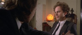 Movie still from “Bad Timing: A Sensual Obsession” (1980), directed by Nicolas Roeg – A man in a suit and tie talking to another man in a suit and tie in front of a lamp; Close Up shot, Over the shoulder angle