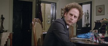 Movie still from “Bad Timing: A Sensual Obsession” (1980), directed by Nicolas Roeg – A man sitting at a dining room table in a suit; Close Up shot, Over the shoulder angle