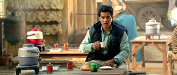 A man sitting at a table drinking a cup of coffee