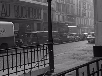 Movie still from “Band of Outsiders” (1964), directed by Jean-Luc Godard – A black and white photo of a city street; Wide shot, High angle