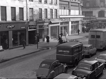Movie still from “Band of Outsiders” (1964), directed by Jean-Luc Godard – A black and white photo of a city street; Extreme Wide shot, High angle