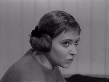 Movie still from “Band of Outsiders” (1964), directed by Jean-Luc Godard – A black and white photo of a woman with a bun; Close Up shot, Over the shoulder angle