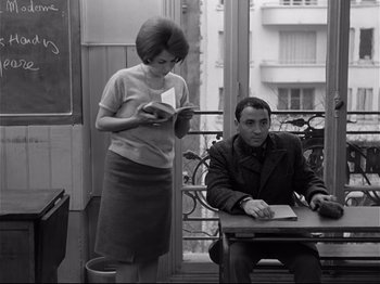 Movie still from “Band of Outsiders” (1964), directed by Jean-Luc Godard – A man and a woman sitting at a table; Medium shot, Low angle
