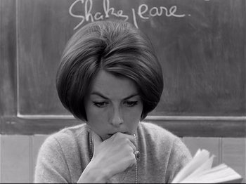 Movie still from “Band of Outsiders” (1964), directed by Jean-Luc Godard – A black and white photo of a woman in front of a chalkboard; Close Up shot, Over the shoulder angle