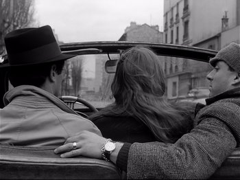 Movie still from “Band of Outsiders” (1964), directed by Jean-Luc Godard – A man and a woman sitting in the back of a car; Medium shot, High angle