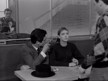 Movie still from “Band of Outsiders” (1964), directed by Jean-Luc Godard – A man and a woman sitting at a table in a restaurant; Medium shot, Over the shoulder angle