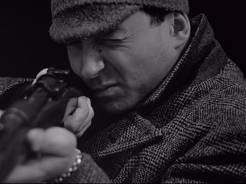 Movie still from “Band of Outsiders” (1964), directed by Jean-Luc Godard – A black and white photo of a man holding a bird; Close Up shot, Low angle