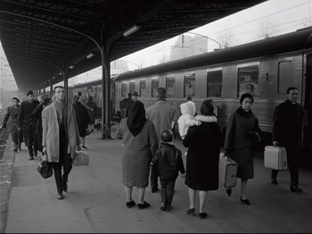 Movie still from “Band of Outsiders” (1964), directed by Jean-Luc Godard – A black and white photo of people at a train station; Wide shot, Low angle
