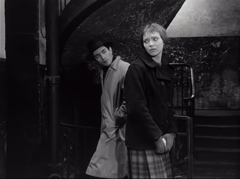 Movie still from “Band of Outsiders” (1964), directed by Jean-Luc Godard – A man and a woman standing next to each other; Medium shot, Low angle