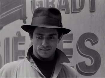 Movie still from “Band of Outsiders” (1964), directed by Jean-Luc Godard – A black and white photo of a man wearing a hat; Close Up shot, Low angle