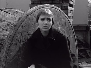 Movie still from “Band of Outsiders” (1964), directed by Jean-Luc Godard – A black and white photo of a woman sitting in a chair; Close Up shot, High angle