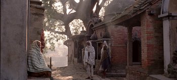 Movie still from “Baraka” (1992), directed by Ron Fricke – Two men in white robes standing next to a tree; Wide shot, Low angle