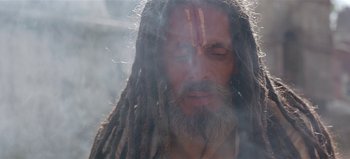 Movie still from “Baraka” (1992), directed by Ron Fricke – A man with long dreadlocks and a long beard; Close Up shot, Low angle