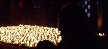 Movie still from “Baraka” (1992), directed by Ron Fricke – A man sitting in front of a fire at night; Close Up shot, Over the shoulder angle