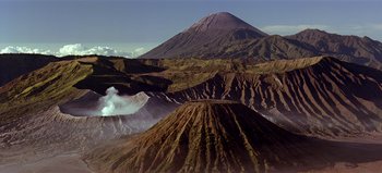 Movie still from “Baraka” (1992), directed by Ron Fricke – A view of a mountain range with a volcano in the background; Extreme Wide shot, High angle