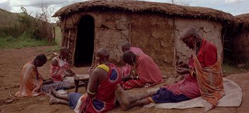 Movie still from “Baraka” (1992), directed by Ron Fricke – A group of men sitting in front of a hut; Wide shot, High angle