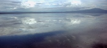 Movie still from “Baraka” (1992), directed by Ron Fricke – A body of water that has clouds in the sky; Extreme Wide shot, High angle