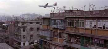 Movie still from “Baraka” (1992), directed by Ron Fricke – An air plane flying over a building; Extreme Wide shot, Low angle
