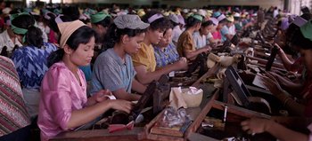 Movie still from “Baraka” (1992), directed by Ron Fricke – A group of women sitting at a table working; Medium shot, High angle