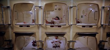 Movie still from “Baraka” (1992), directed by Ron Fricke – A person in a room with a bed; Wide shot, Overhead angle