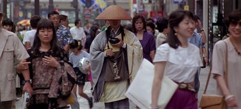 Movie still from “Baraka” (1992), directed by Ron Fricke – A man wearing a hat is looking at his cell phone; Wide shot, Low angle