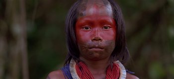 Movie still from “Baraka” (1992), directed by Ron Fricke – A person with a face paint and a necklace; Close Up shot, High angle