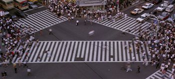 Movie still from “Baraka” (1992), directed by Ron Fricke – A group of people walking across a crosswalk; Extreme Wide shot, Overhead angle